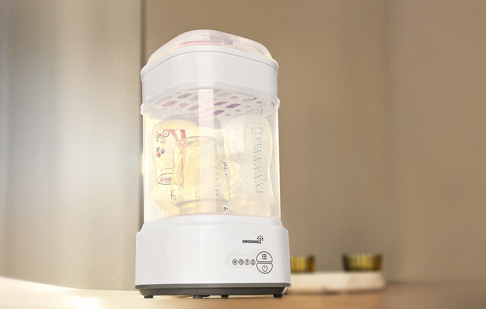 Sterilizer in operation with illuminated interior and visible steam rising around the bottles