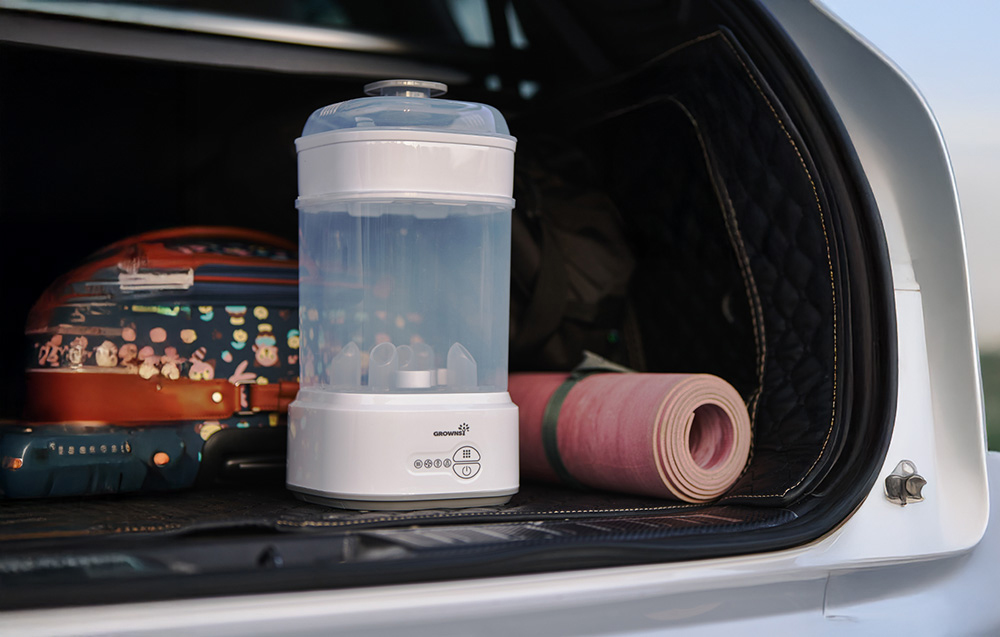 Sterilizer placed in the trunk of a car next to a suitcase and a mat