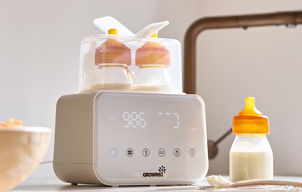 Bottle warmer with two bottles inside and one standing next to it on the kitchen counter