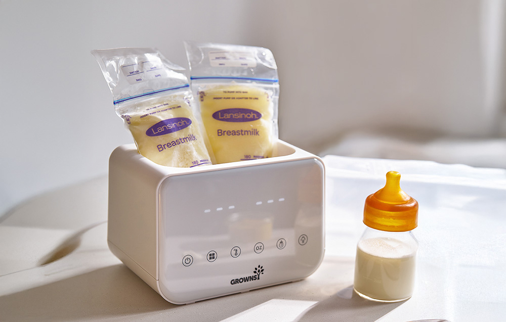 A warmer with two milk bags labeled Breastmilk and a bottle standing next to it