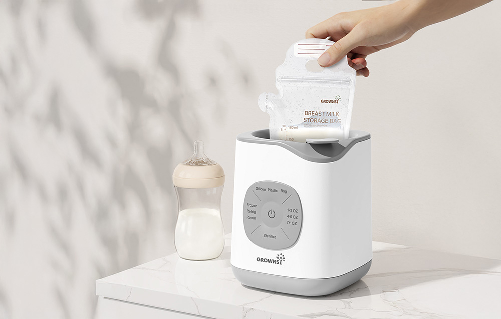 Hand placing a milk bag into the warmer, with a bottle standing next to it